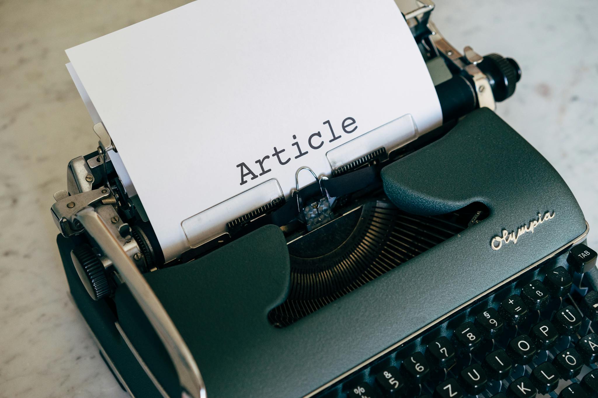 Close-up of a vintage typewriter with a paper sheet displaying 'Article' in retro font.
