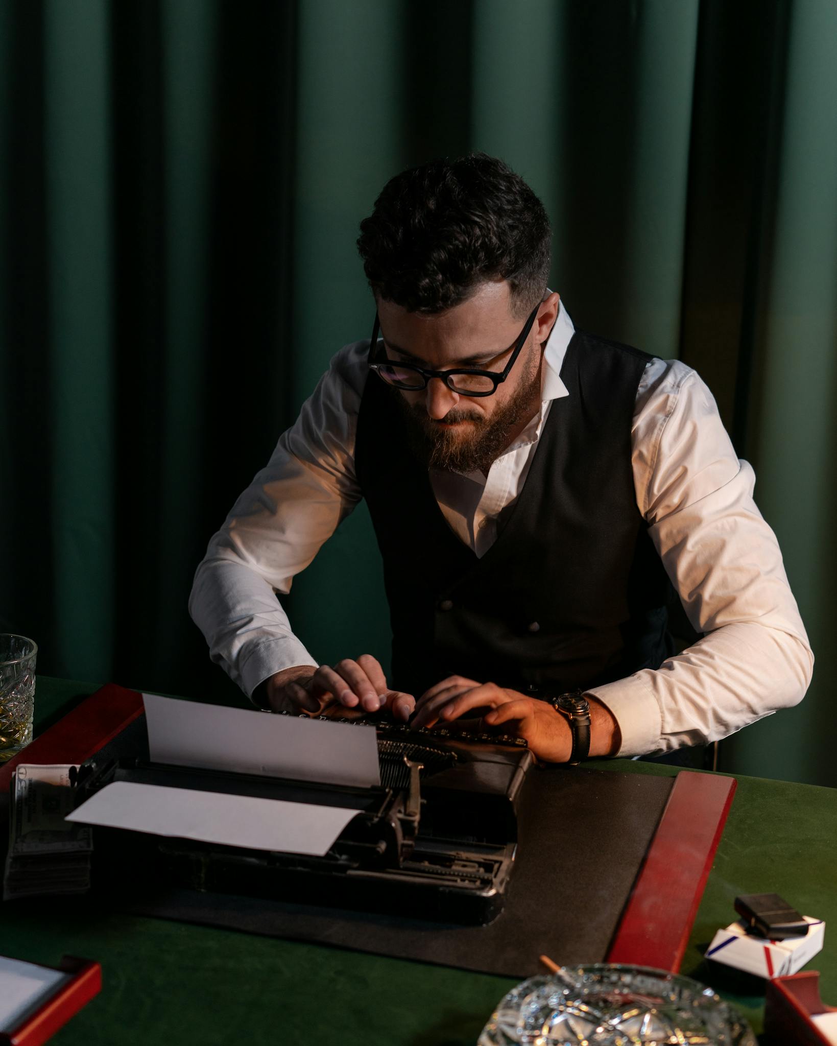 Man intently typing on a vintage typewriter in a dimly lit room, capturing a nostalgic workplace scene.